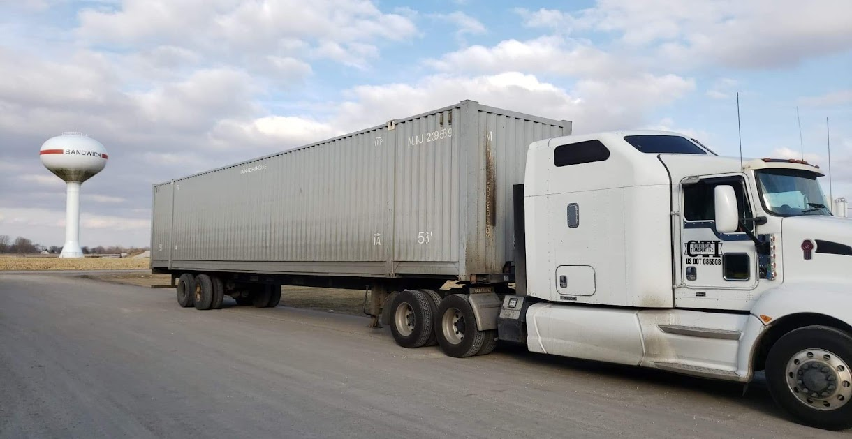 White tractor and intermodal trailer near Sandwich water tower